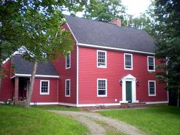 House plan exterior: Two-story red house with a gabled roof, central entry with portico, and attached side section with covered porch.