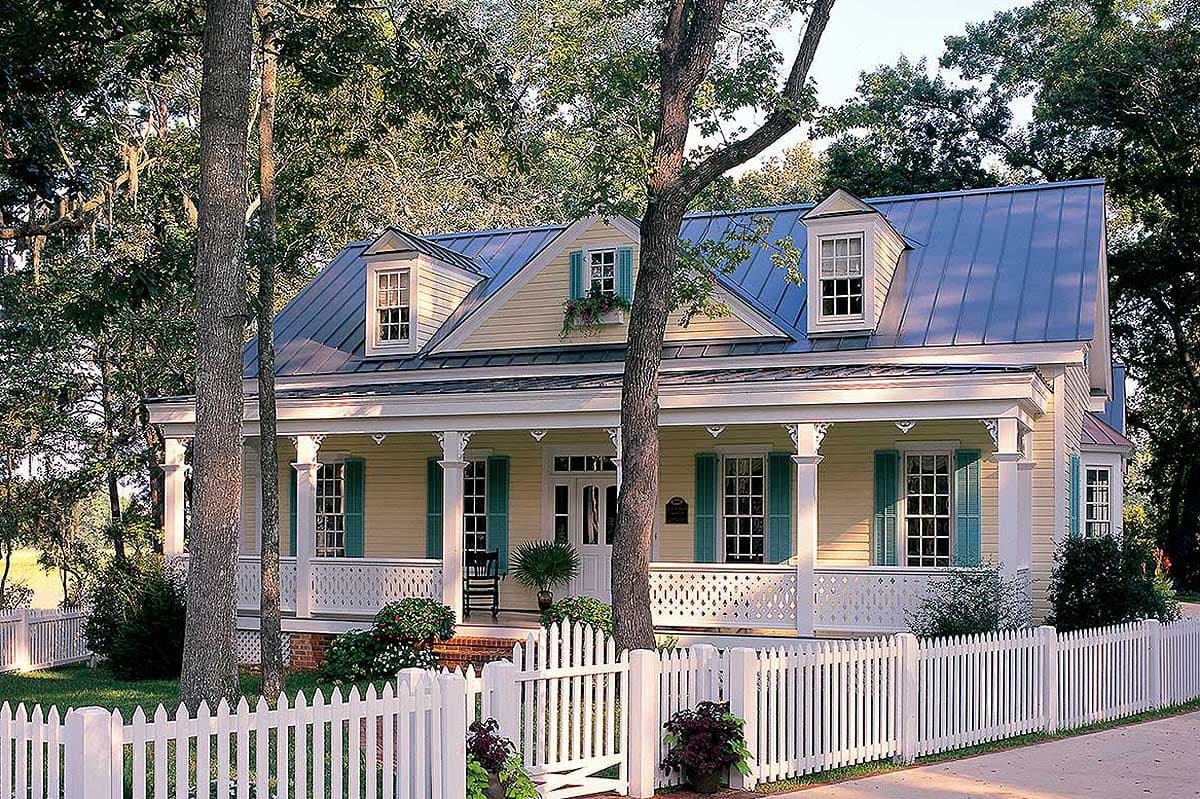 House plan exterior: two-story cottage with wraparound porch, dormer windows, and metal roof.