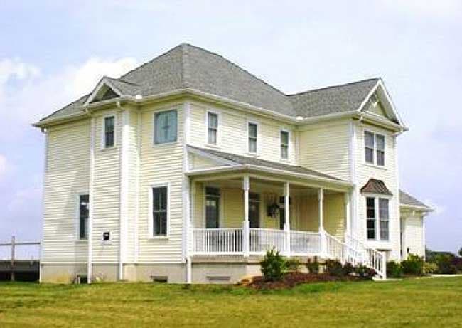 House plan exterior: Two-story home with wraparound porch, gables, dormers, and bay window.