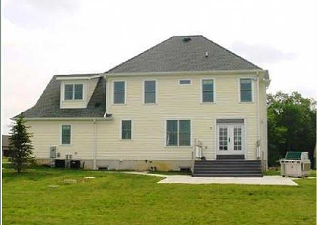 House plan exterior, two stories, cream siding, hip roof with dormer, double door rear access, and large side yard.