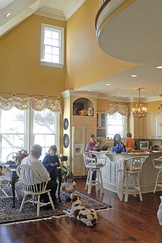 Interior view of open-concept kitchen and dining area with vaulted ceiling, island with seating, and large windows.