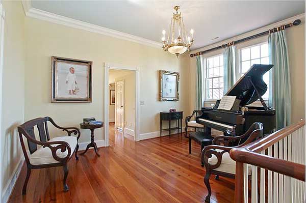 Interior view of a room with a grand piano, two chairs, a small table, and a chandelier.
