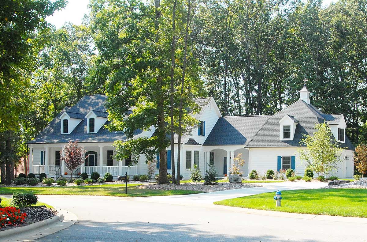 House plan exterior of a white two-story Modern Farmhouse with a wraparound porch, dormers, and a cupola.