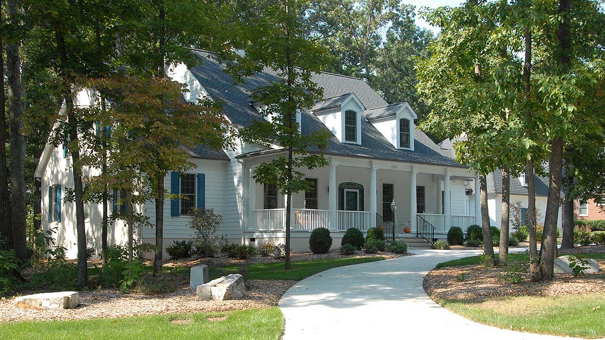 House plan exterior featuring a wrap-around porch, gabled dormers, and white siding.