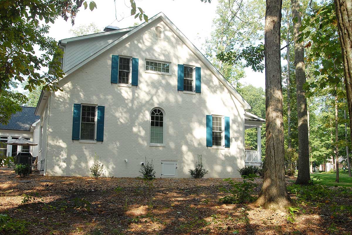 House plan exterior, two stories, white brick, blue shutters, arched window, dormer, and porch.