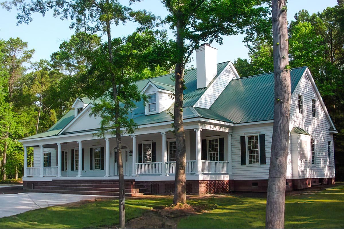 House plan exterior: White Southern Colonial style, one and a half stories, wrap-around porch with columns, dormer windows, and metal roof.