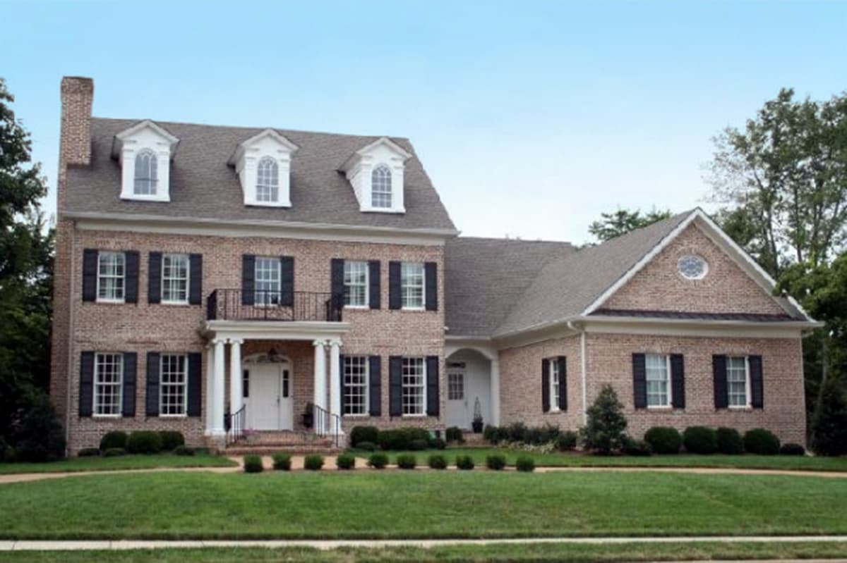 Two-story brick house plan with a central portico, arched dormers, and black shutters.