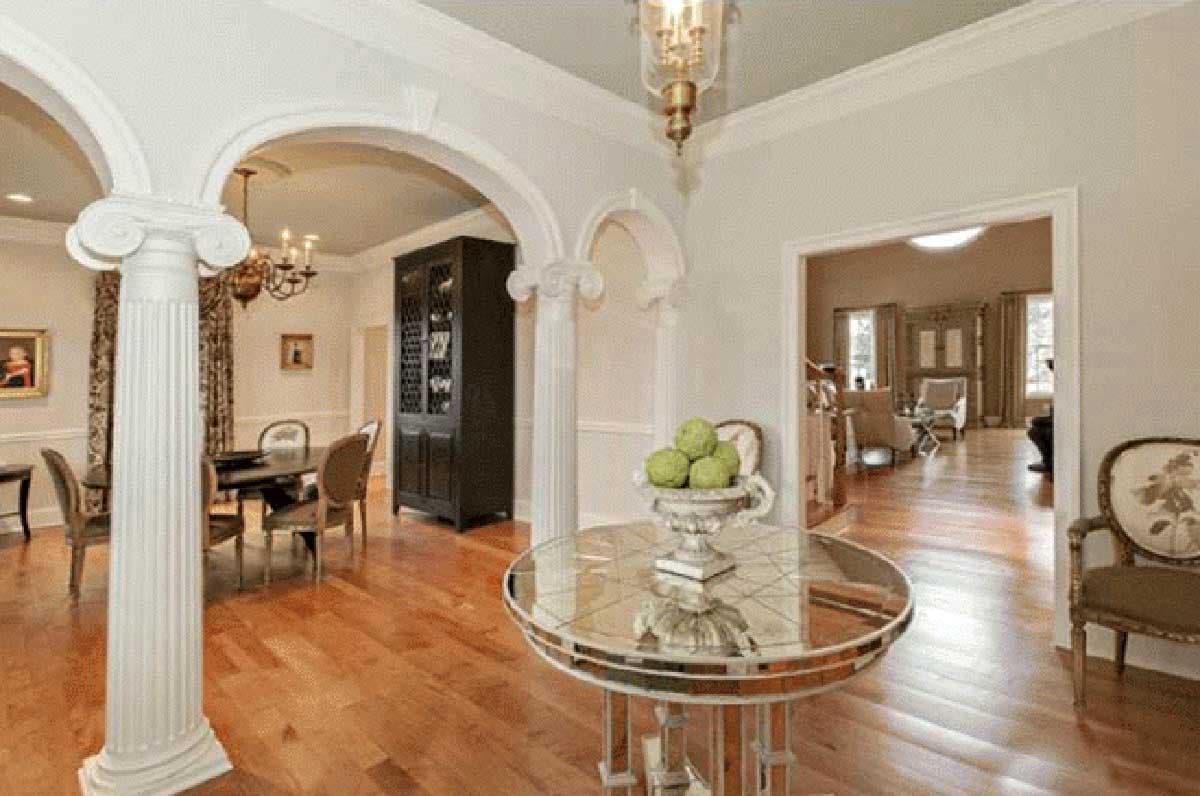Interior view of a foyer with Corinthian columns, arches, and view into a dining room and living room.