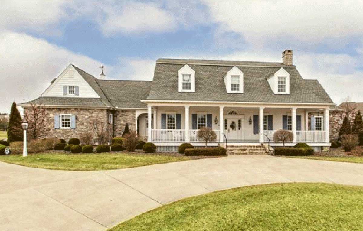 House plan exterior with stone accents, wrap-around porch, gambrel roof, and multiple dormers.