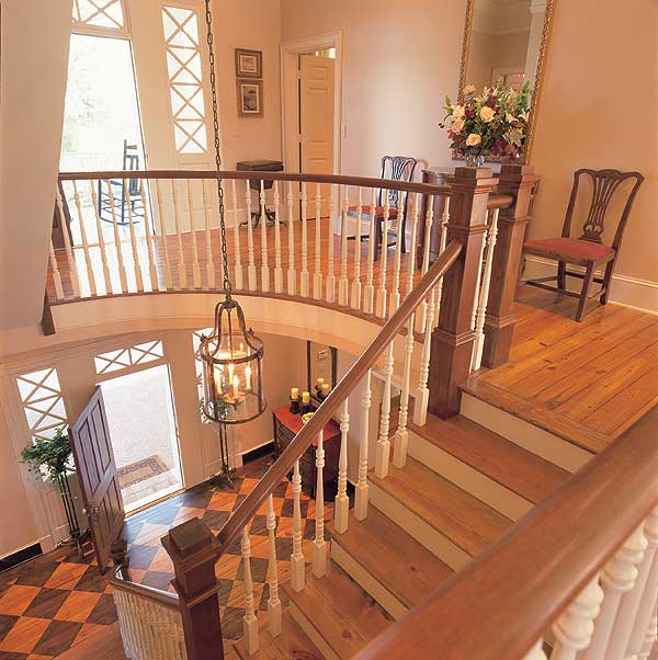 Grand foyer with curved staircase, diamond patterned flooring, and a decorative lantern.