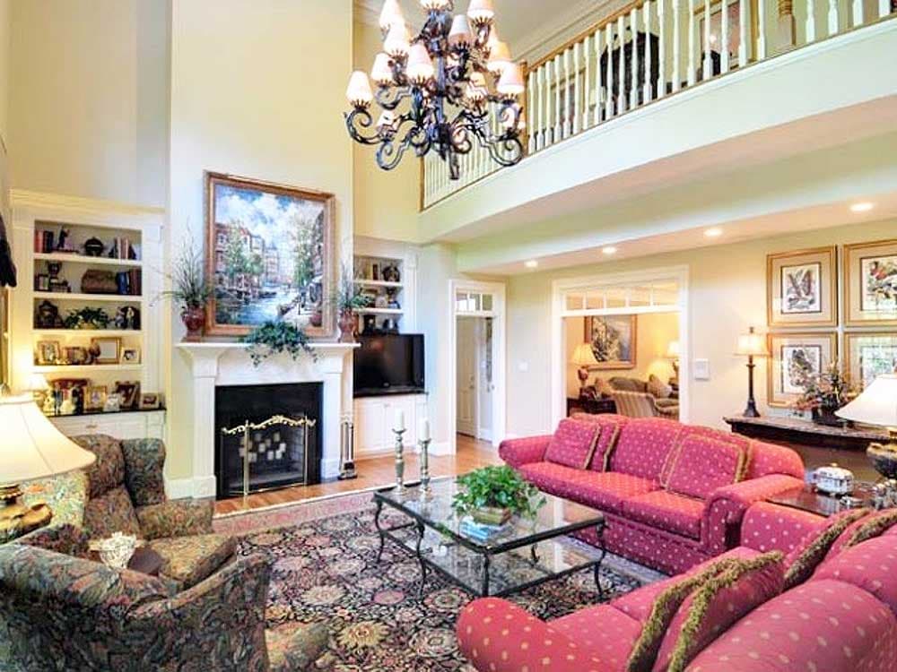 Interior view of a two-story great room with fireplace, built-in bookshelves, and a balcony overlook.