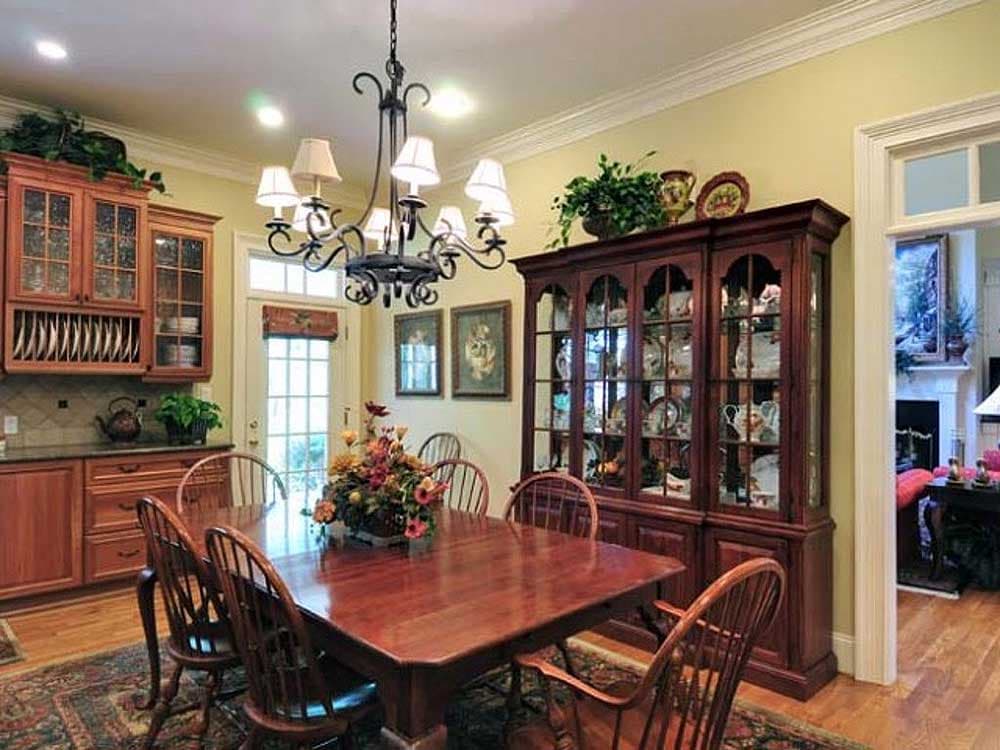 Dining room with wood table, chairs, hutch, and cabinetry. View of door and adjacent living space.