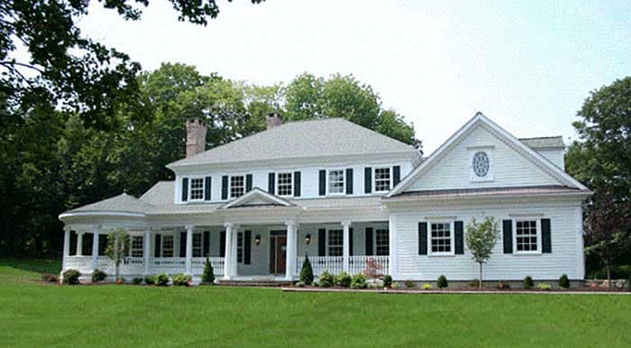 House plan exterior: Two-story traditional home with wraparound porch, gables, and a prominent central entrance.