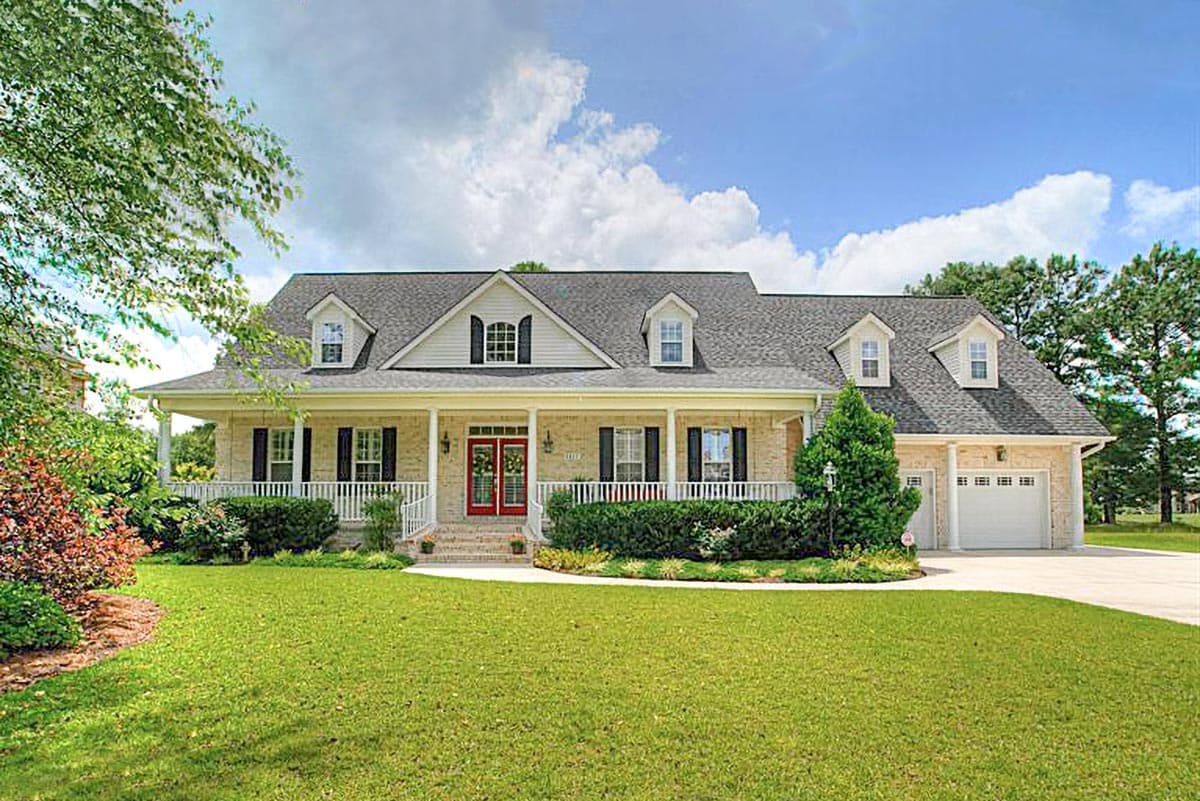 Two-story house plan exterior with wraparound porch, dormers, and a side-entry two-car garage.