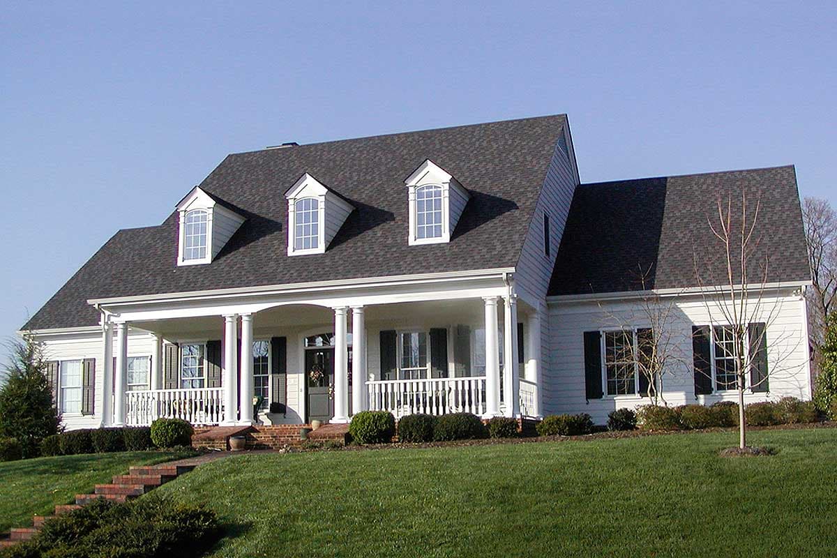 House plan exterior: One-story traditional home with wrap-around porch, columns, and three gabled dormers.