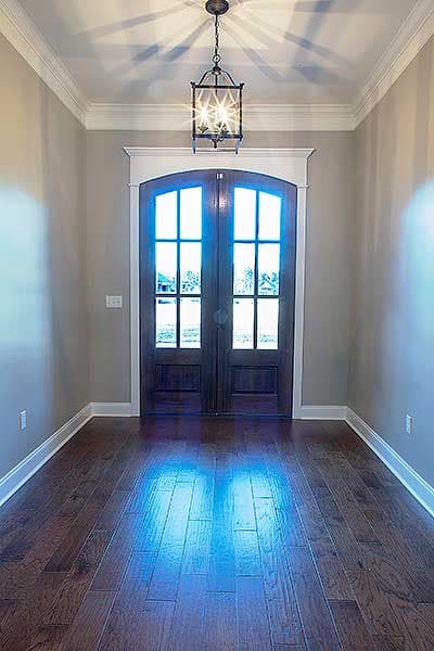Foyer with double arched doors, dark wood floors, and a decorative pendant light.