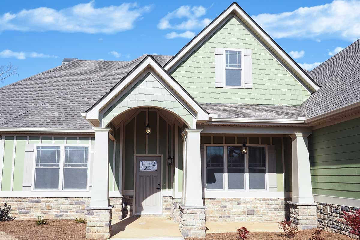 House plan exterior: Modern Farmhouse style, two-story, with stone base, arched entry porch, gable dormer, and double-hung windows.