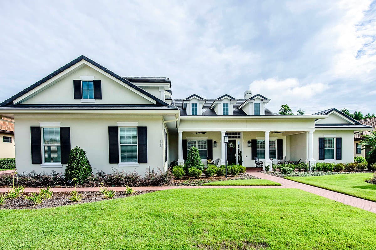 House plan exterior featuring a two-story design with a covered porch, dormers, and gabled roofline.