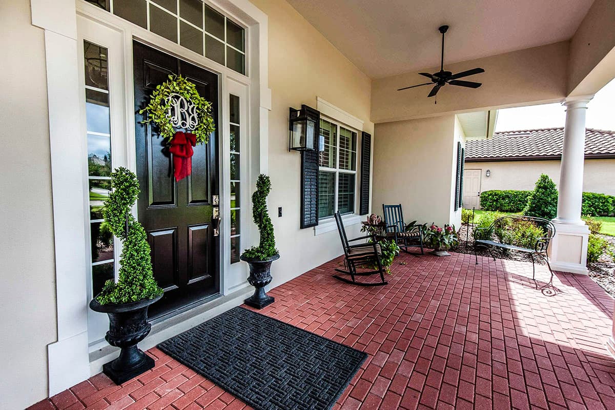 House plan exterior featuring a covered front porch with brick pavers, columns, and a double door entrance.