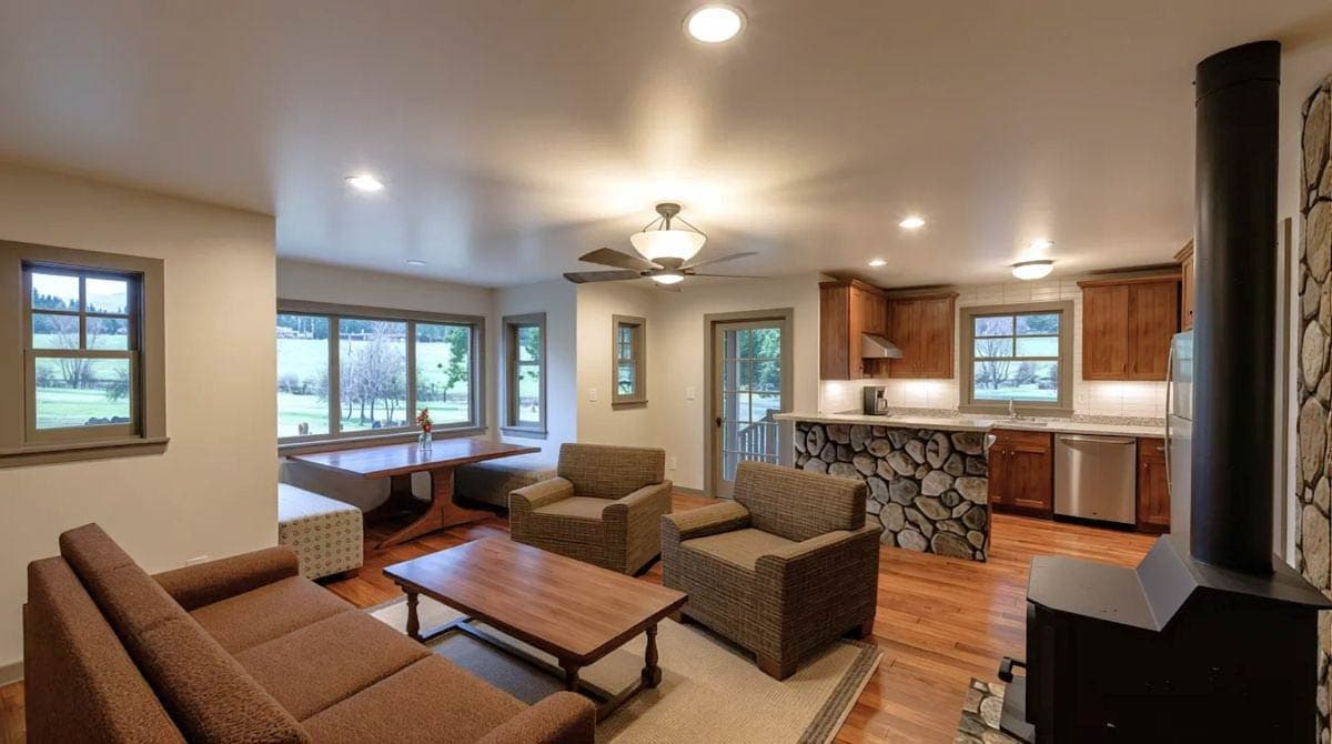 Open concept living area with wood stove, dining table, and kitchen with stone island.