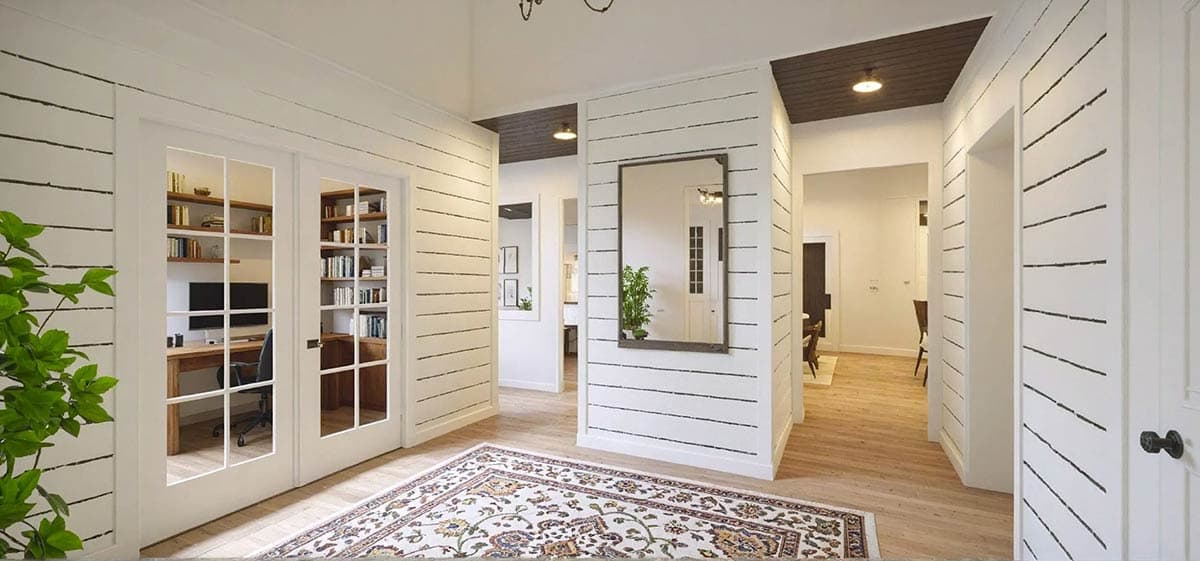 Interior view of a house with shiplap walls, French doors to a study, and a decorative rug on hardwood floors.