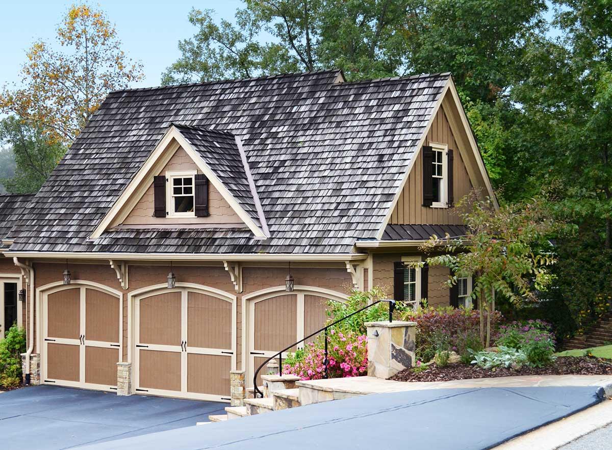 House plan exterior with three-car garage, prominent gables, and shingled roof.
