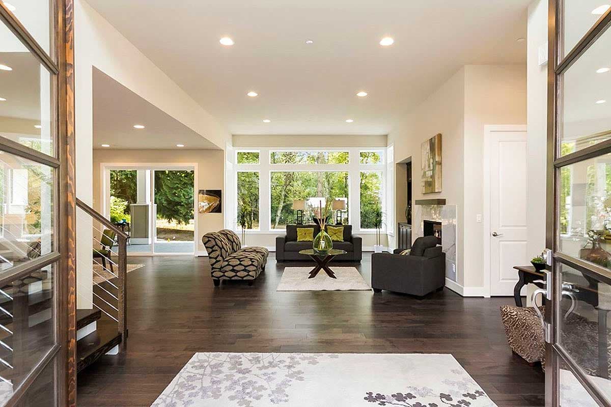 Open-concept living room with large bay windows, fireplace, and modern furnishings.
