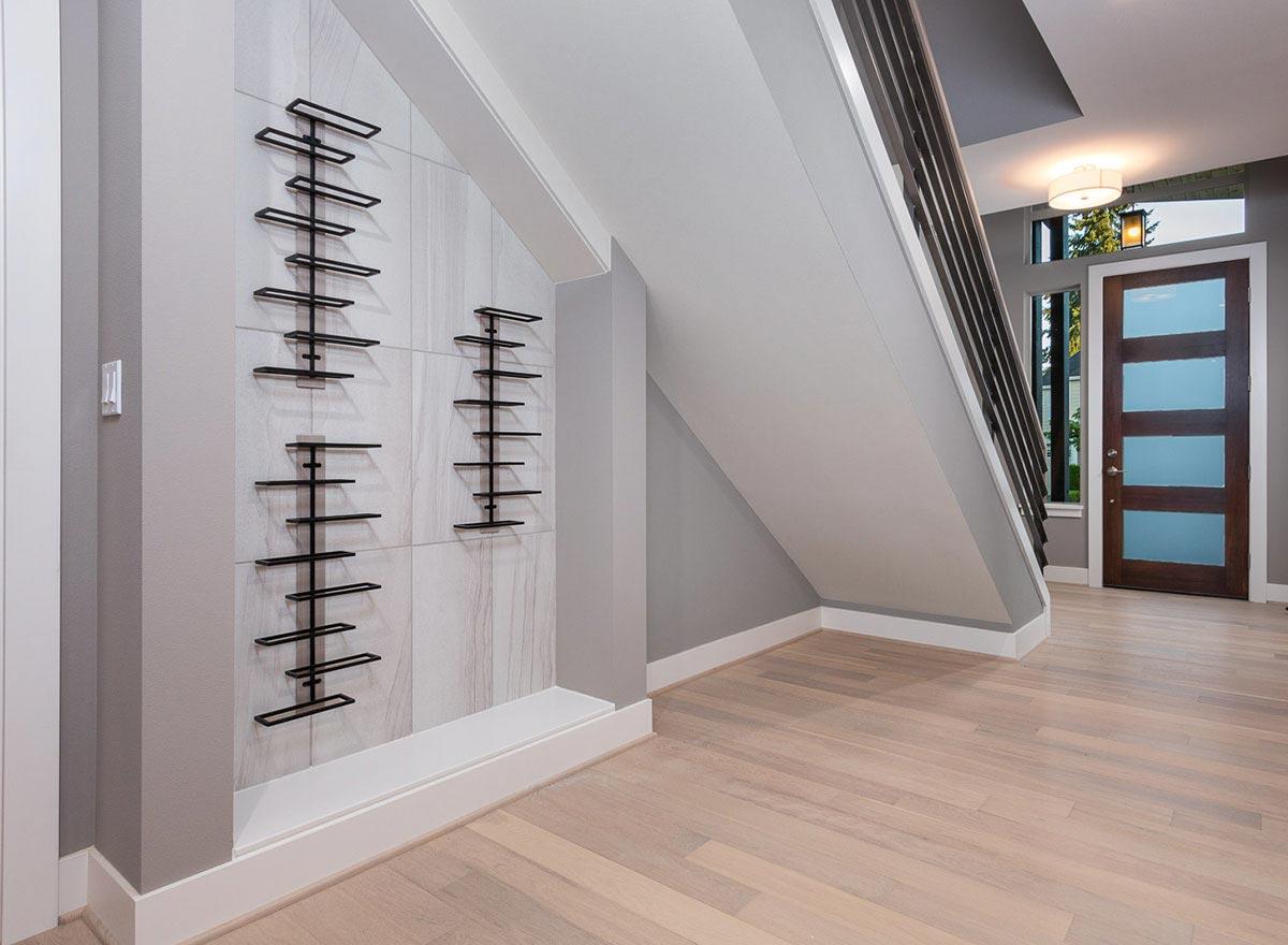 Interior view: Modern entryway with tiled accent wall featuring decorative metal wine racks and wood flooring.