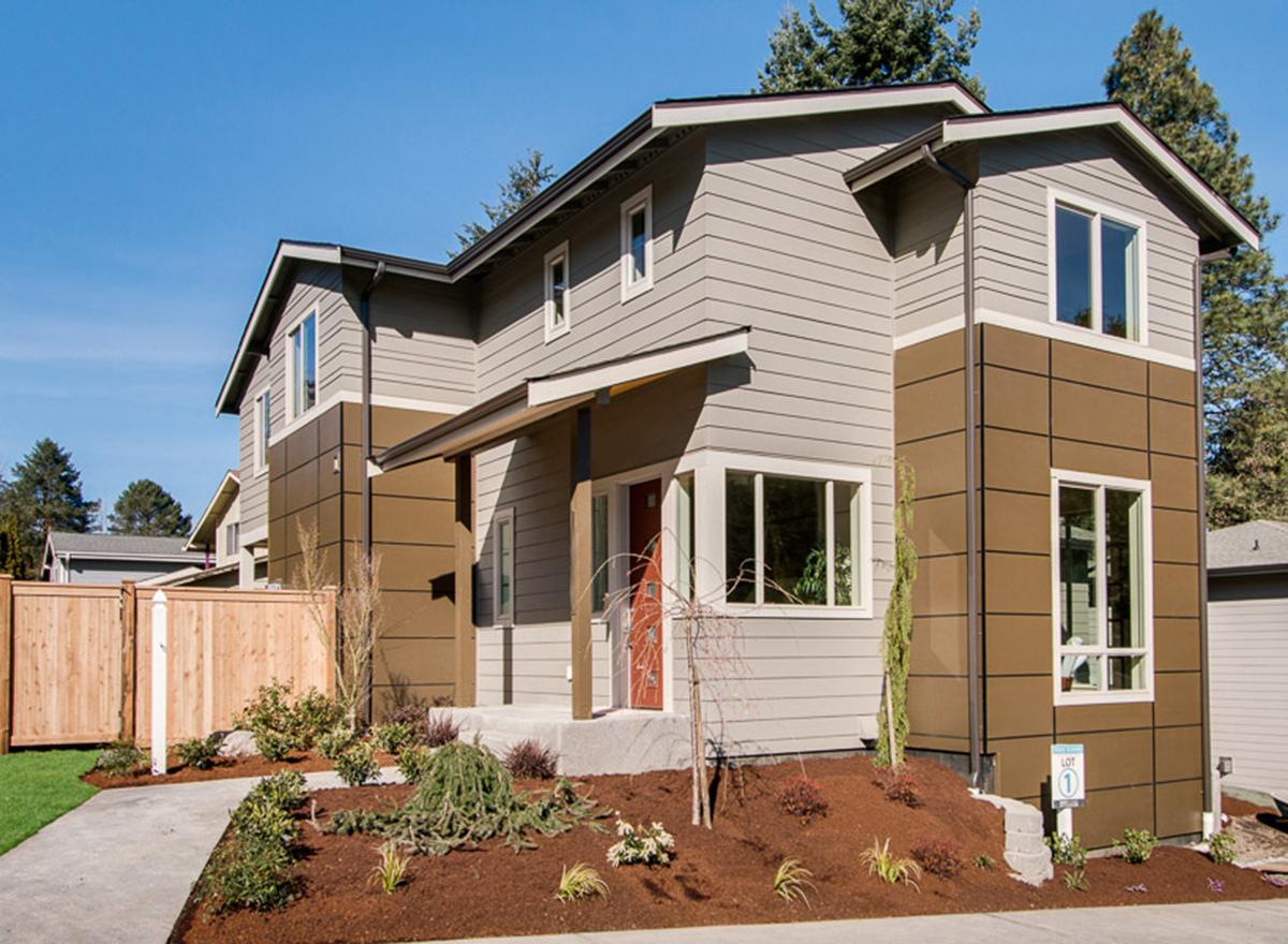 Modern house plan exterior, two stories, with beige horizontal siding, brown paneled sections, and a covered entryway.