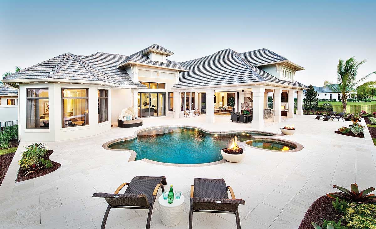 Luxury home exterior with a pool, lounge chairs, and fire pit.  A covered patio leads to the home.