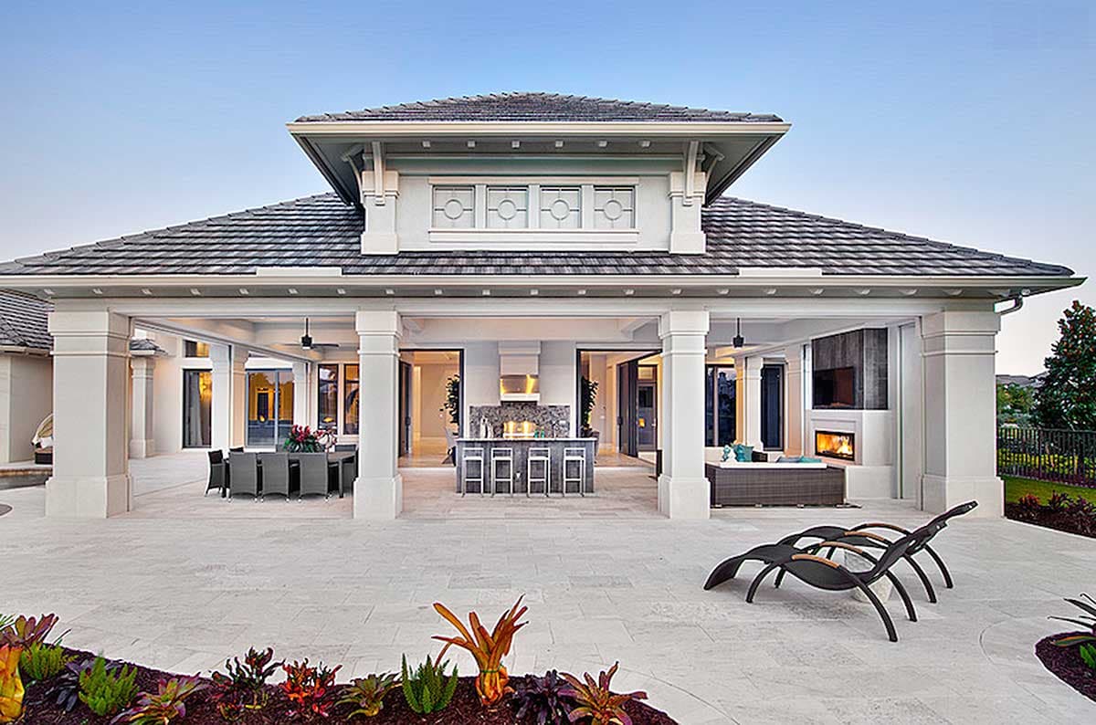 Luxurious outdoor living area of a house featuring a patio, kitchen, dining area, and a fireplace.