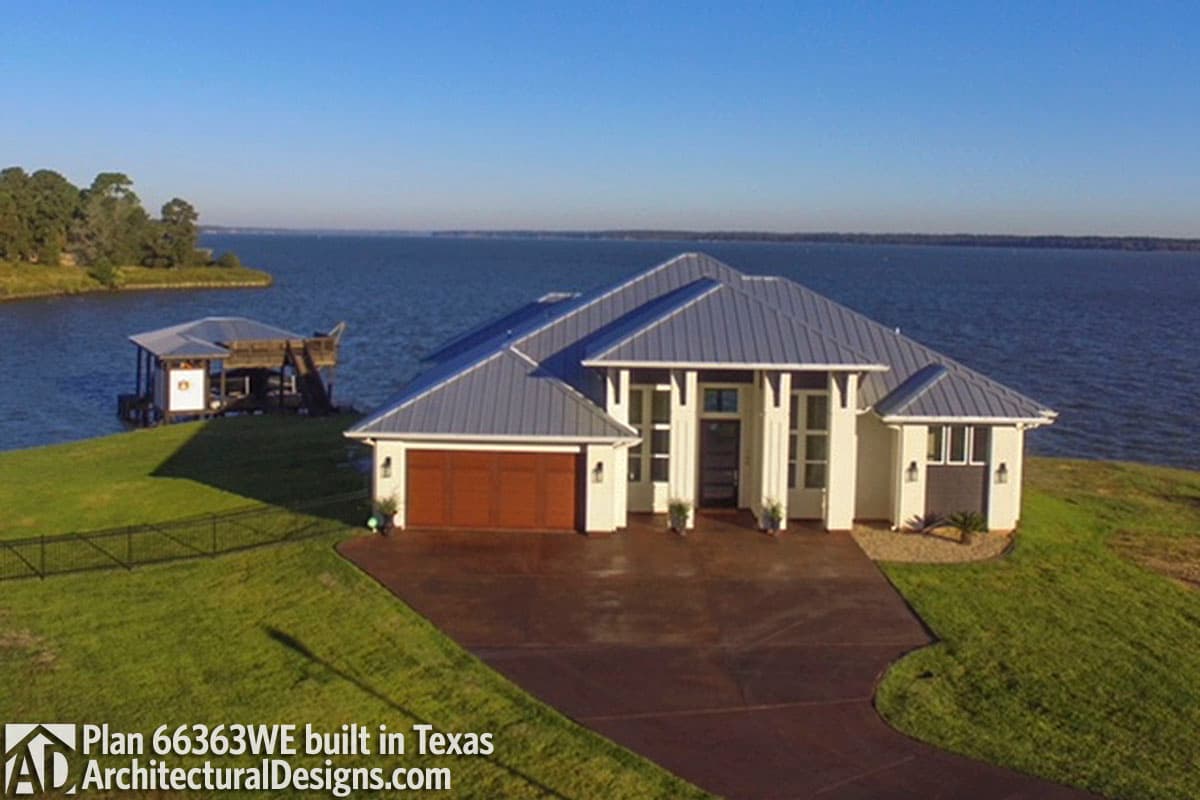 House plan exterior: Modern ranch with metal roof, attached two-car garage, and covered entryway with white columns.