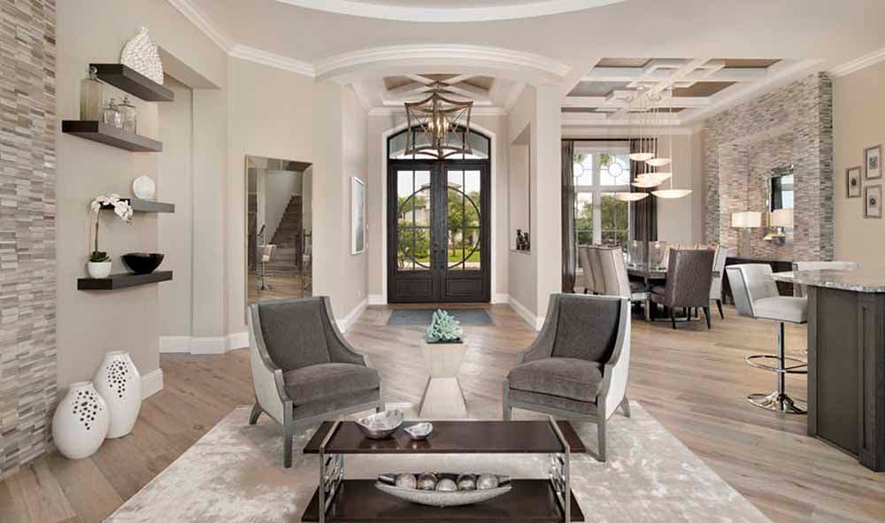 Interior view of a grand entryway with double doors, coffered ceiling, and seating area.