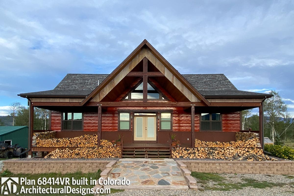 House plan exterior with a large A-frame gable, covered porch, wood siding, and prominent stone walkway.