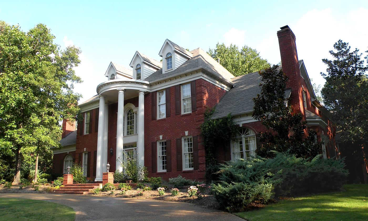 House plan exterior: Two-story brick home with a curved portico, pedimented dormers, and a tall brick chimney.