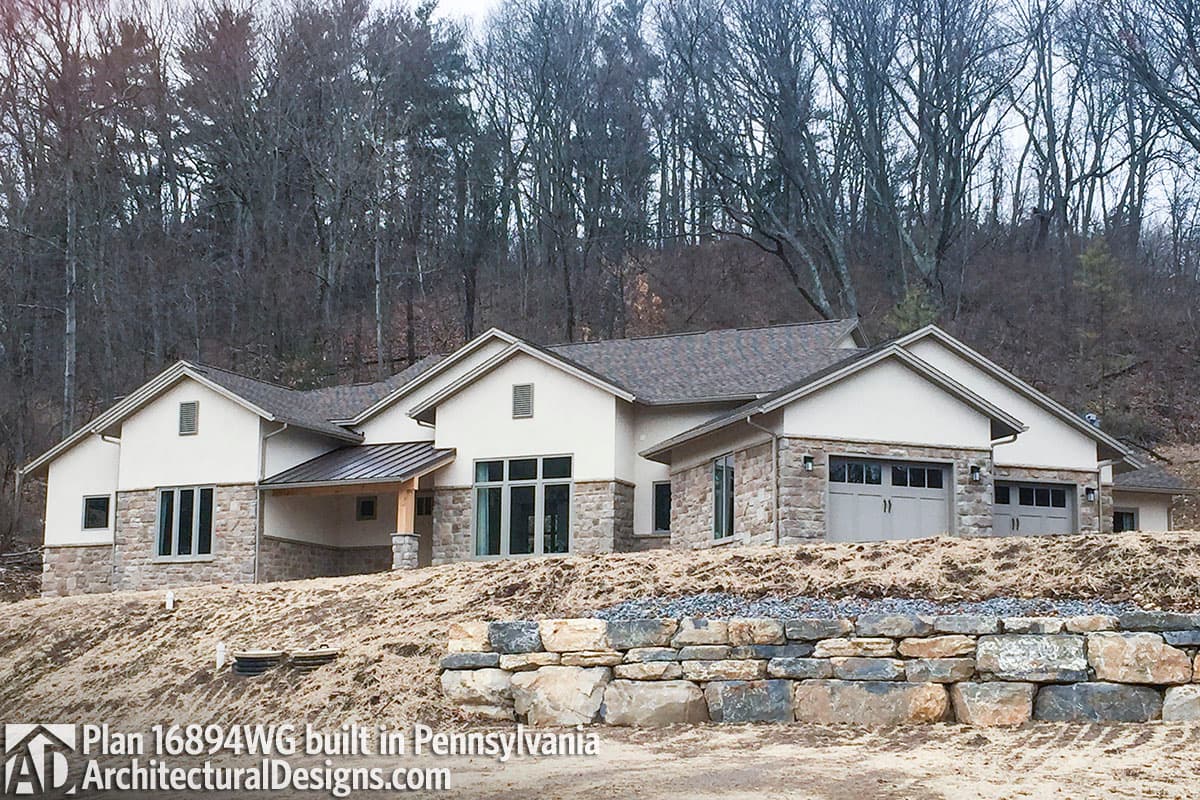 House plan exterior with stone base, stucco walls, multiple gables, covered entrance, and three-car garage.