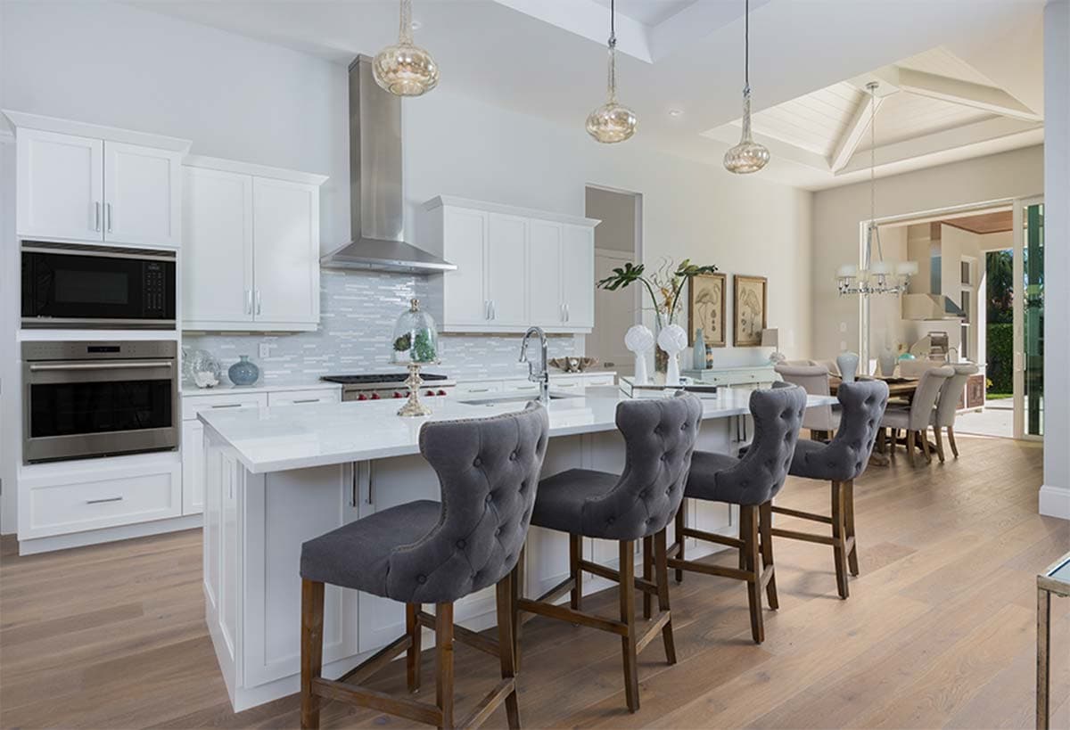 Modern kitchen with white cabinetry, stainless steel appliances, island with bar seating, and open access to dining area.