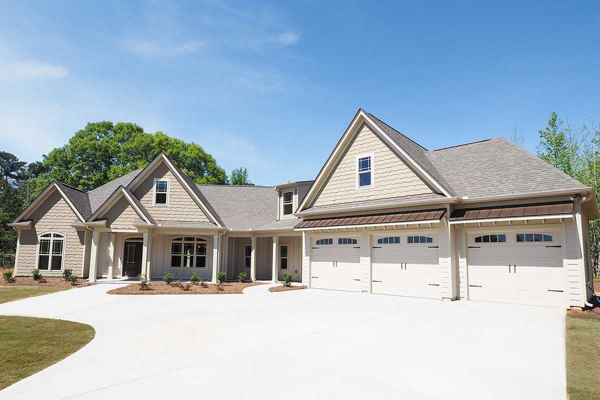 House plan exterior. One-story house with gabled roof, dormers, and a three-car garage. Features include a covered entry and a long driveway.
