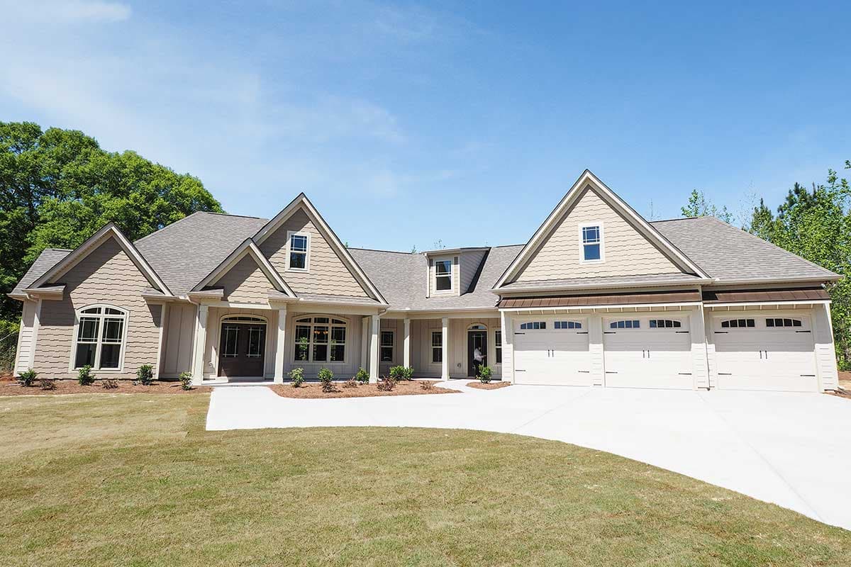 House plan exterior: Ranch-style home with gable dormers, arched windows, and a three-car garage.