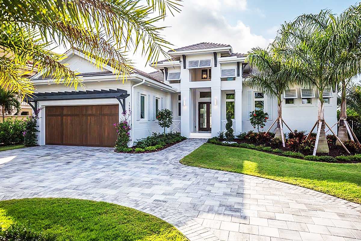 House plan exterior. Two-story home with a hipped roof, attached garage, and a covered entry. Features include a portico and open shutters.