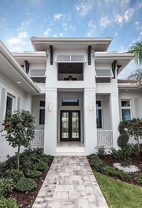 House plan exterior with double doors, upper balcony, and modern rooflines.