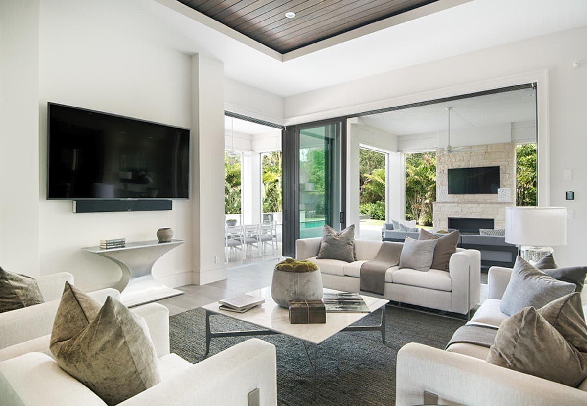Living room with sectional sofas, coffee table, stone fireplace, and large sliding glass doors to an outdoor patio.
