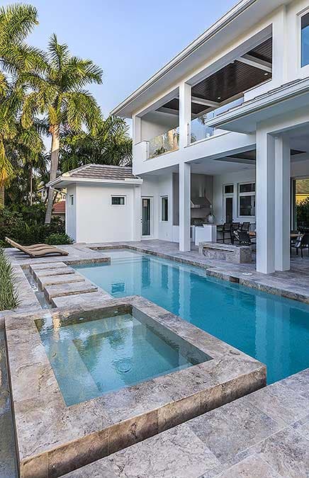 Modern house exterior with multi-level balconies, a long swimming pool, and spa.