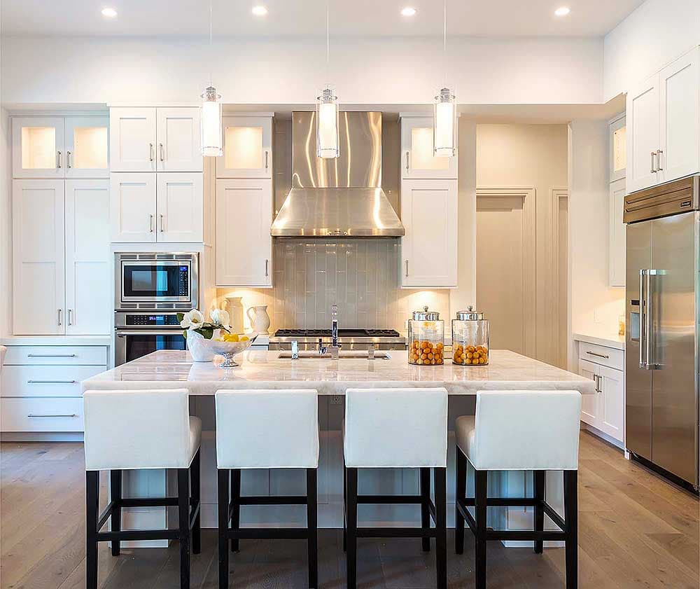 Kitchen with white cabinets, stainless steel appliances, large island with seating, and pendant lighting.