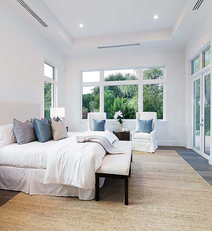 Interior rendering of a spacious bedroom with a large bed, seating area, and abundant natural light from floor-to-ceiling windows.