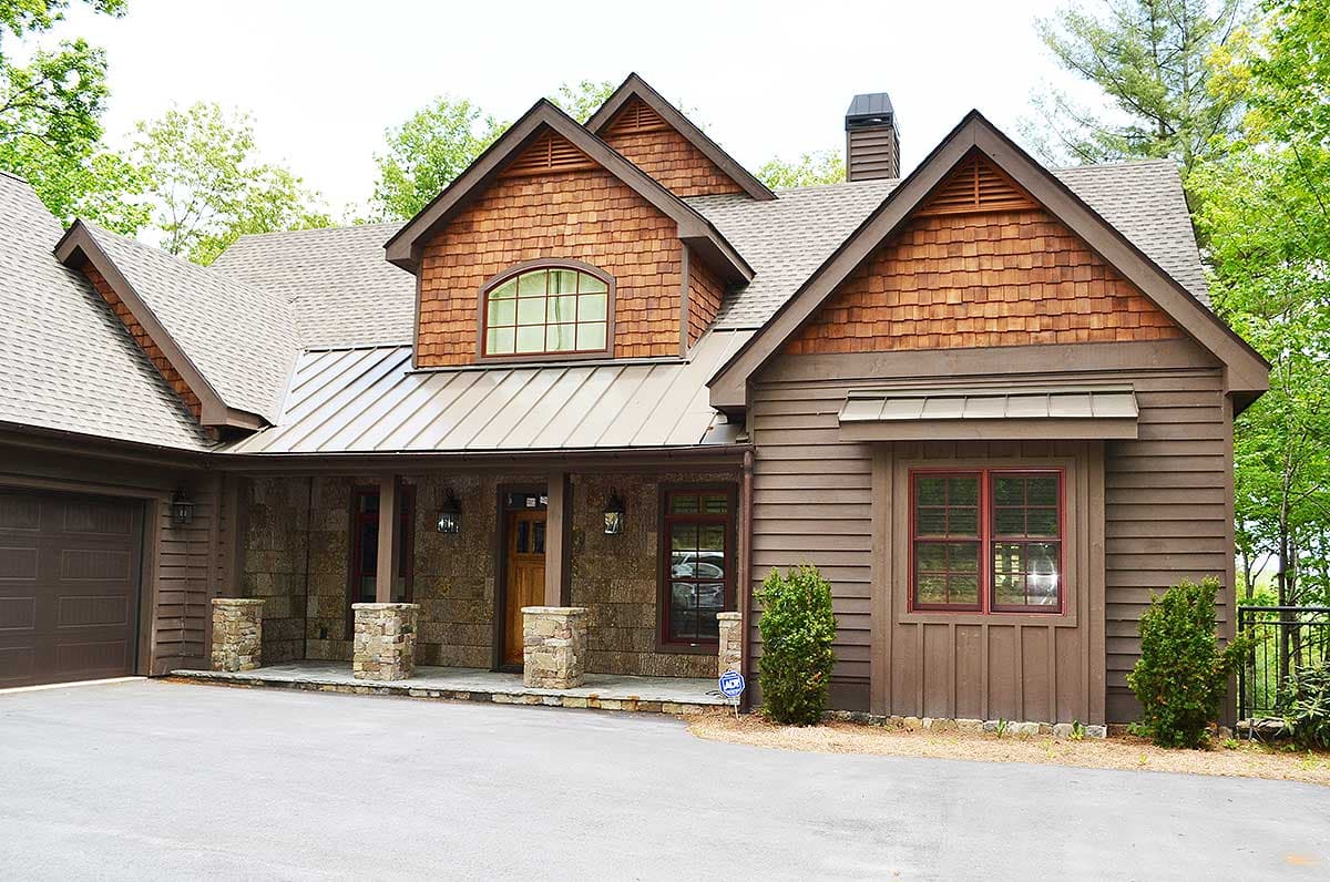 House plan exterior: Two-story Craftsman style with stone accents, metal roof, prominent gables with cedar shakes, and covered porch.