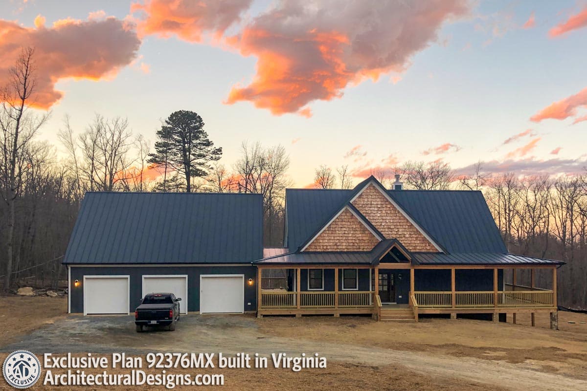 Modern farmhouse exterior with metal roof, wraparound porch, dormer, and attached three-car garage.