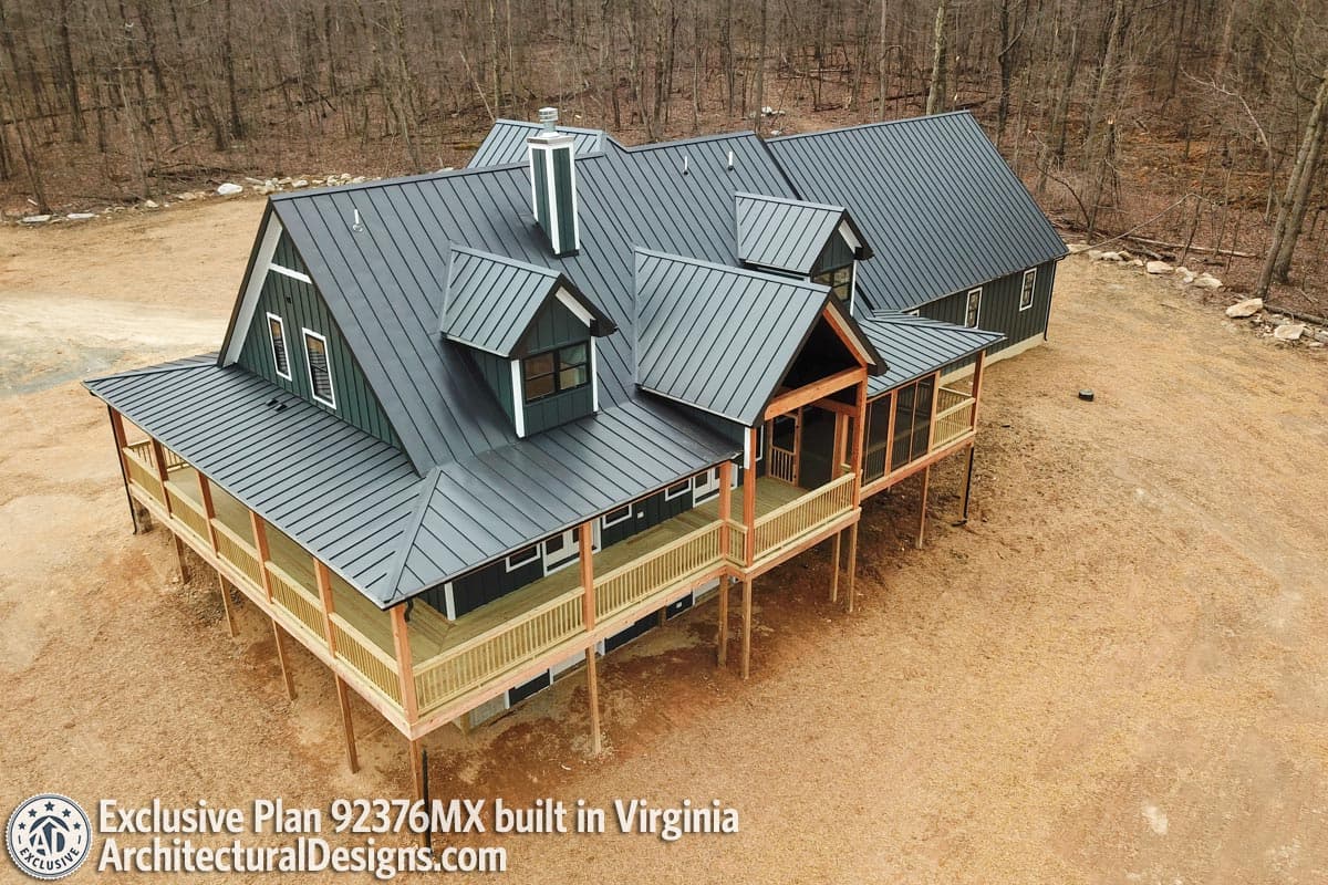 House plan exterior with dark siding, metal roof, wraparound porch, dormers, and screened porch.