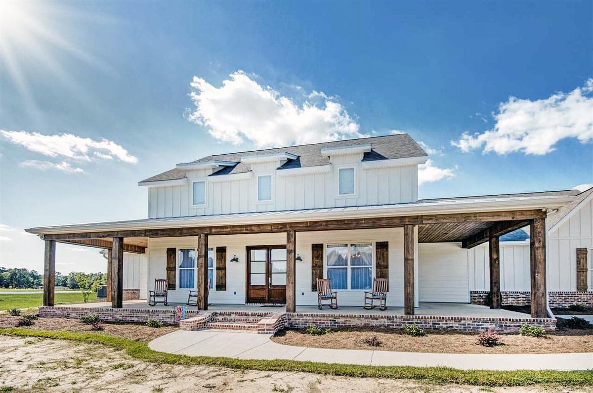 House plan exterior, Modern Farmhouse style, two stories, wrap-around porch with wooden columns, dormers, and white board and batten siding.