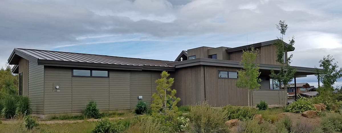 Modern house plan exterior with flat roof, horizontal siding, and large, dark-framed windows.